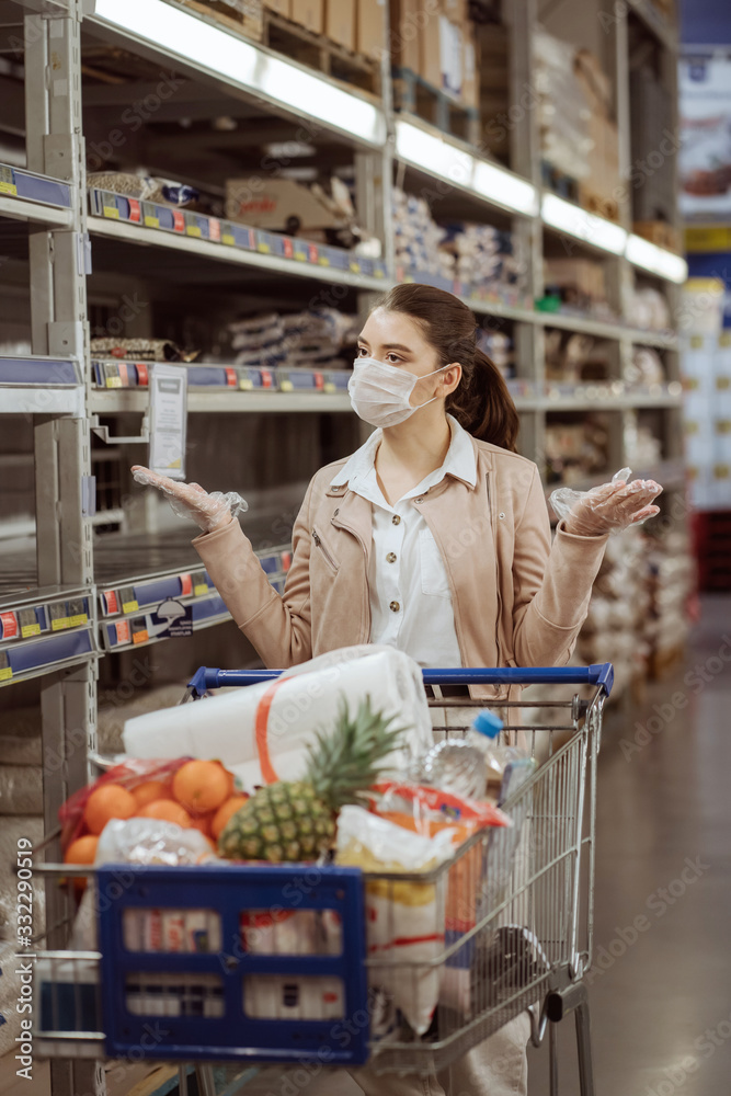 woman with medical mask and gloves in the supermarket can't choose products.
