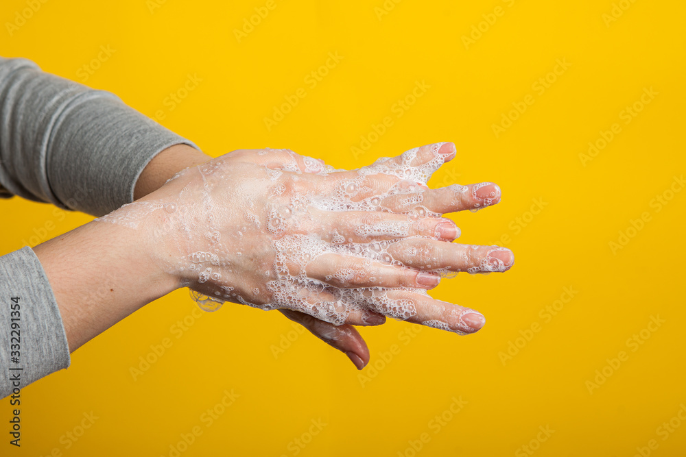 Fototapeta premium female hands hold soap hands between fingers on a yellow studio background. Bright close-up photo. Instructions for proper hand washing.