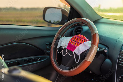 Many face masks are placed on the steering wheel inside the car. © kaentian