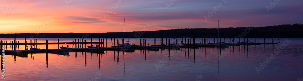 Marina Dock Panorama at Dawn with Sun Rising to a Pink and Purple Clouded Sky Over a Calm Tree Lined River Marina Dock Panorama at Dawn with Sun Rising to a Pink and Purple Clouded Sky Over a Calm Tree Lined River