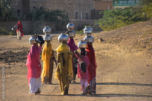 インドのラジャスタン州
ジャイサルメールのクーリー村
水瓶を頭に乗せて運ぶ、インド人女性
民族衣装のサリーを着て働く、美しい姿 photo