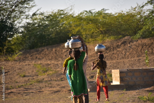 インドのラジャスタン州
ジャイサルメールのクーリー村
水瓶を頭に乗せて運ぶ、インド人少女
民族衣装のサリーを着て働く、美しい姿 photo