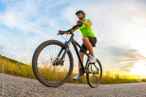Athletic beautiful cyclist rides a bicycle on the road against the backdrop of beautiful nature. hobbies and sports