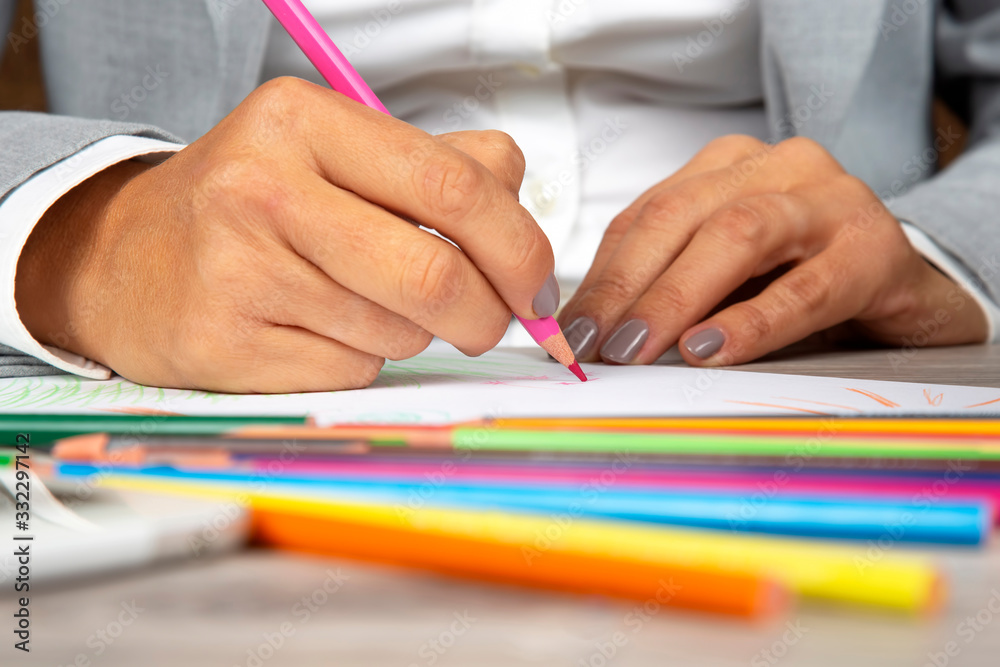 woman's hand in the office draws with crayons on paper woman's hand in the office draws with crayons on paper