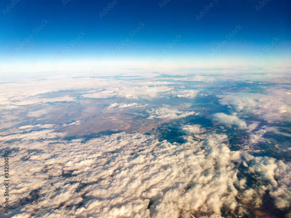Aerial view above the earth. Wide angle of view to white cumulus clouds, earth and space from airplane. Time of sunset