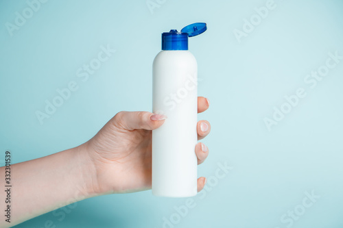 Disinfectant bottle in hand on a blue background. Coronavirus prevention, health protection concept.