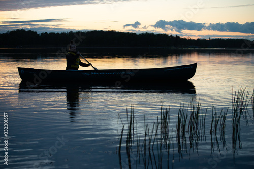 canoe at sunset on a calm body of water photo