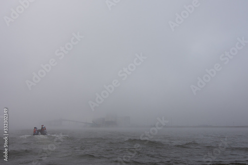foggy day on the churchill river as beluga boats go back toward the port of churchill