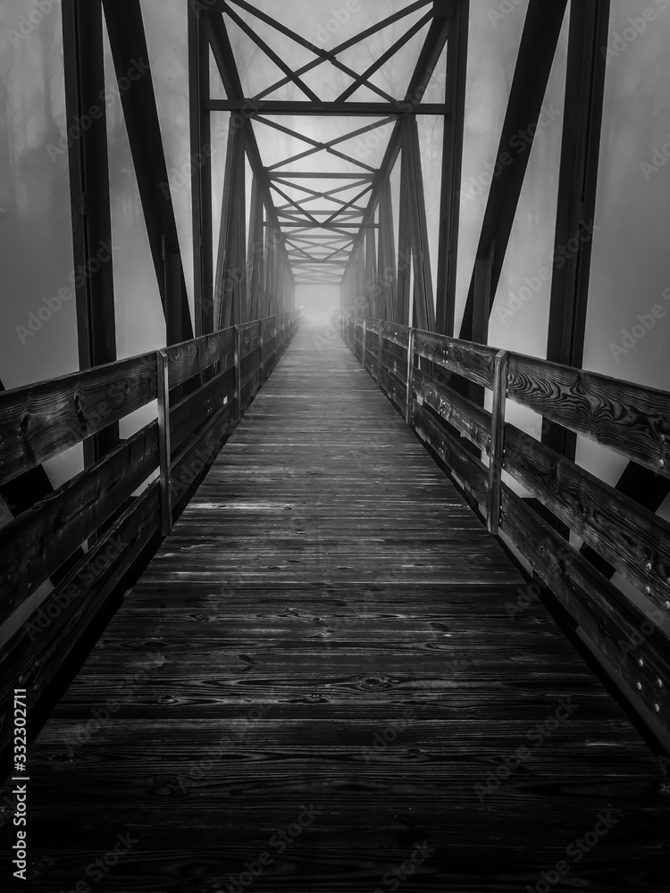 Eerie image of an old truss footbridge on a dark foggy morning at Tims Ford State Park. Eerie image of an old truss footbridge on a dark foggy morning at Tims Ford State Park.