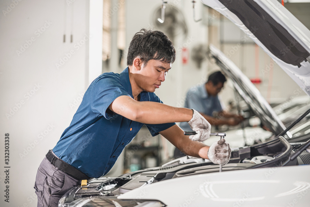 Asian mechanic Checking and repairing the car in maintainance service center which is a part of showroom, technician or engineer professional work for customer, car repair concept