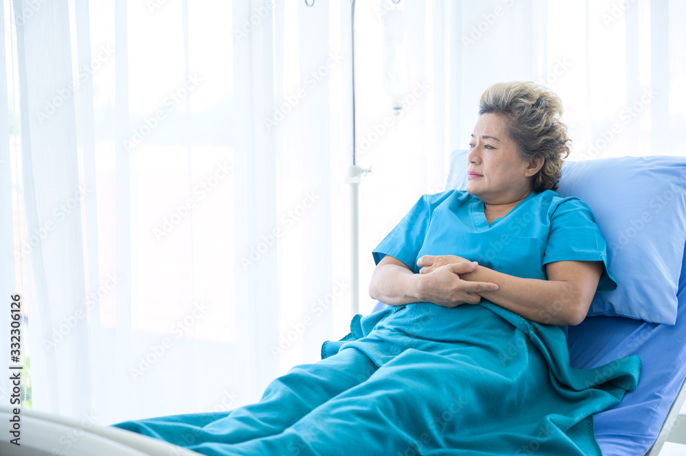 Fototapeta premium Elderly female patients sitting and looking outside with loneliness, On the bed in the hospital