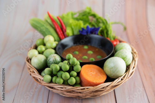 Chili paste paste in a bowl with eggplant, carrots, chili, cucumbers in a basket
