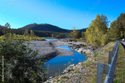 curb by the road. river flowing into the distance. The car is driving on the road. landscape next to the road