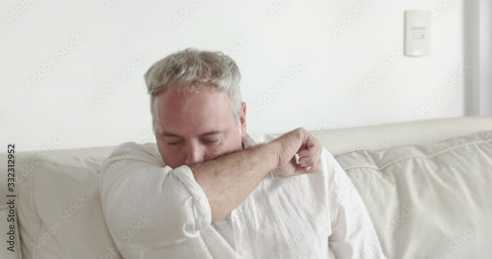 Man Sneezing  or Coughing Correctly To Avoid Spread Virus Like Corona Virus COVID 19 Having An Allergic Symptom Sit On Home Sofa coughing