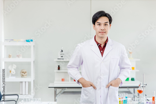 Portrait of Asian young handsome doctor scientist in hospital medical lap dressing white clean uniform looking smile