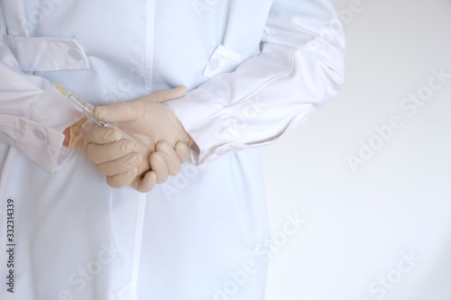 Vaccination concept. Medicine and health concept. coronavirus vaccine.Doctor holds a syringe in his hands behind his back.Doctor's hands in a white medical coat and syringe closeup.