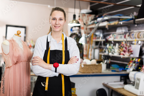 Portrait of woman seamstress who is standing on her workplace