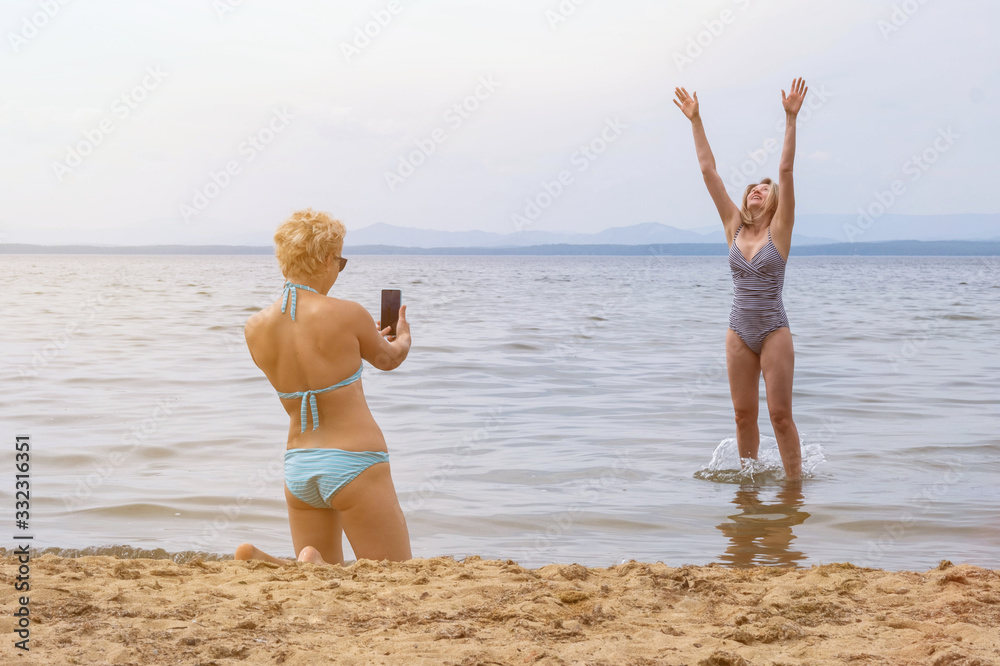 A beautiful short haired girl photographs her friend jumping in a mountain lake A beautiful short haired girl photographs her friend jumping in a mountain lake
