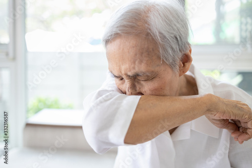 Asian elderly people sneezing,coughing into her sleeve or elbow to prevent spread Covid-19,Corona virus,sick senior woman has flu,fever covering nose,mouth with her arm from dust,air pollution,allergy