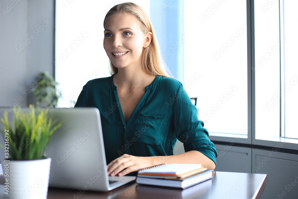 Beautiful smiling business woman is sitting in the office and looking at camera Beautiful smiling business woman is sitting in the office and looking at camera