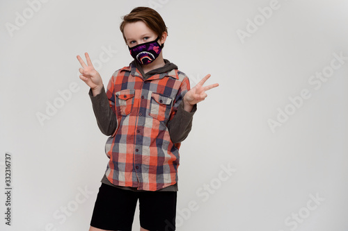 Photo of a masked boy in a plaid shirt on a white background shows his hands to the sides
