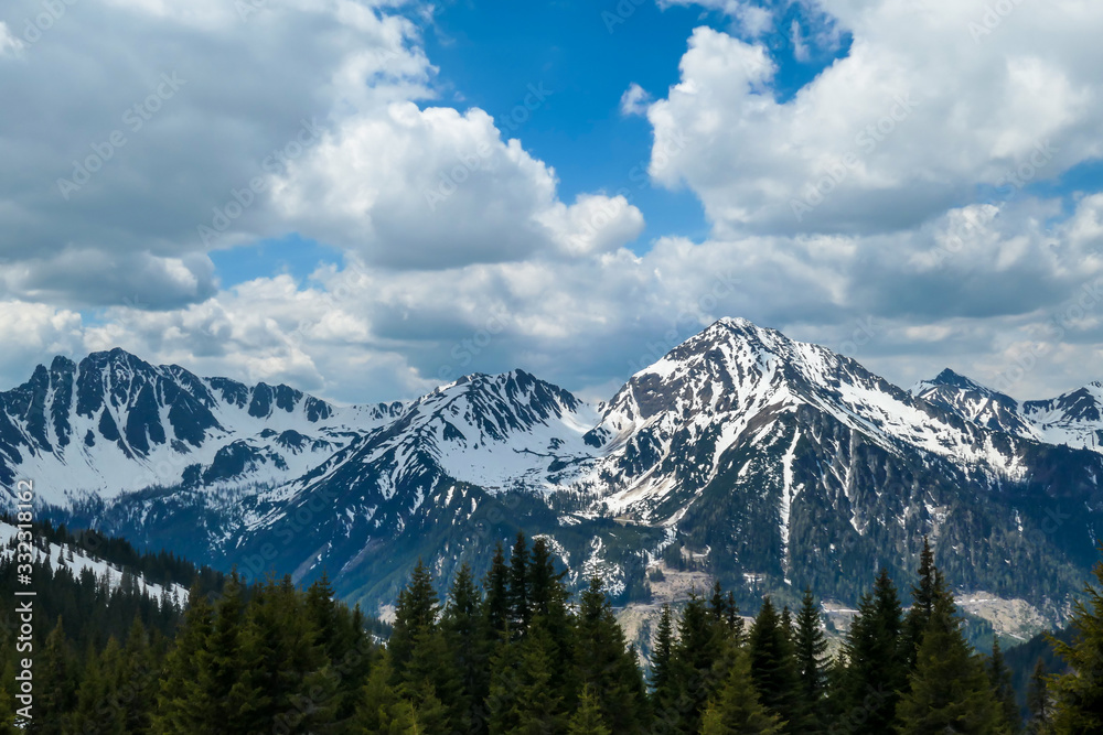 Fototapeta premium A view on a massive mountain range, partially covered with snow, seen from Himmeleck, Austria. Dangerous mountain climbing. Spring slowly coming to high altitudes. Awakening after hibernation