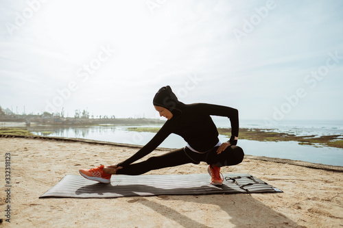 woman with muslim sport wear stretching. sporty female using head scarf exercising