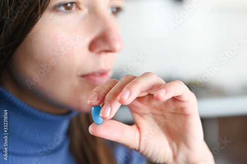 Close-up of a womans hand with a glass of water taking medicine. Pills in a box. Coronavirus treatment concept