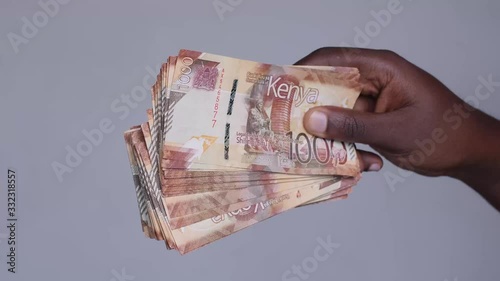 Close up shot of male hand revealing  Kenyan shillings money cash from the right. Employee salary. Cash money payment photo