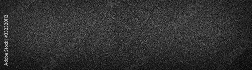 Ultra wide rough black surface. Panoramic background with darkened edges. Texture of flat and grainy sandpaper or panorama of uneven wall material. photo