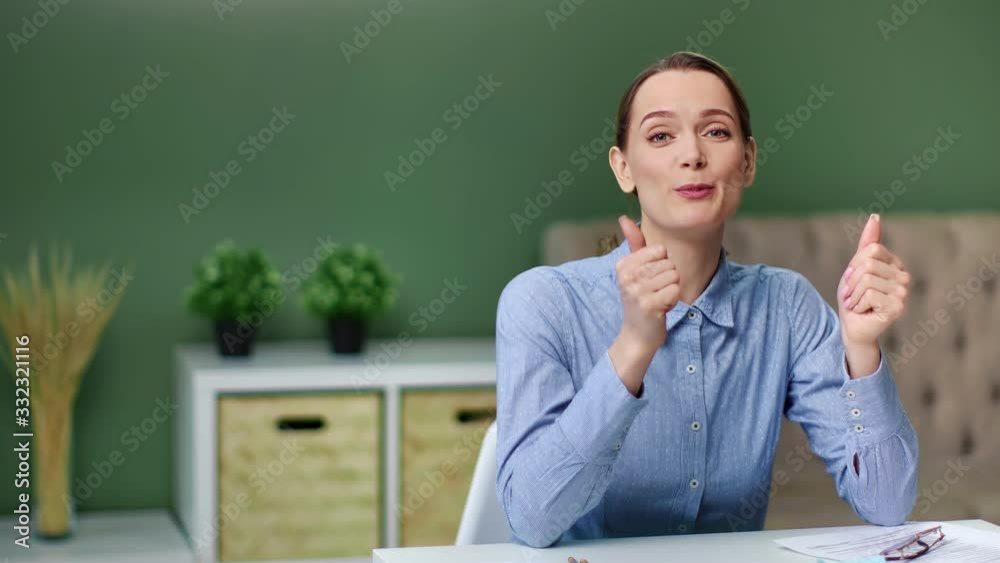 Smiling female blogger sitting at table talking showing gesture cool. Medium shot on RED camera Smiling female blogger sitting at table talking showing gesture cool. Medium shot on RED camera