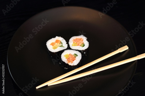 Sushi futomaki with smoked salmon on black plate