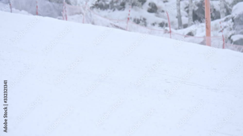 Athlete in sport clothes skiing on snowy hillside at ski resort in daytime Athlete in sport clothes skiing on snowy hillside at ski resort in daytime