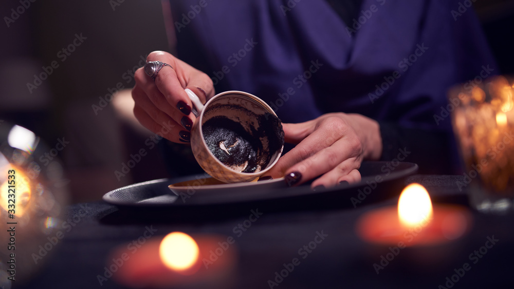 Female fortune teller divines on coffee grounds at table with ball of predictions