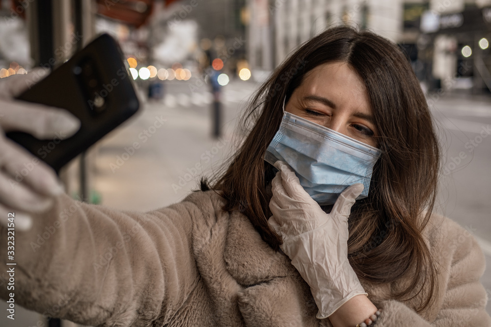 Φωτογραφία Woman wearing medical mask and gloved holding phone in hand and taking selfie