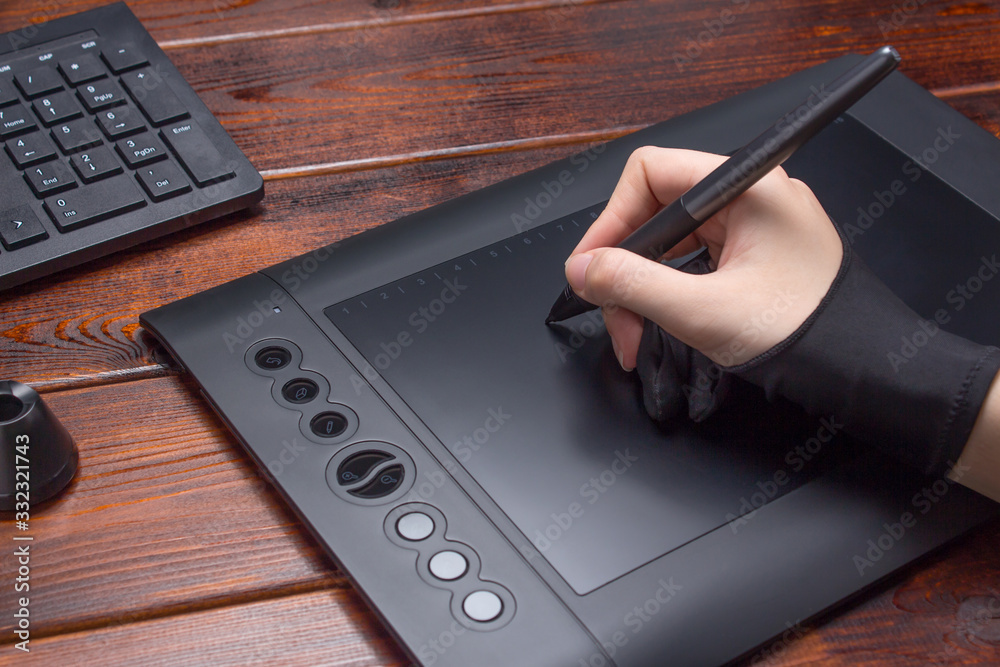 The hand draws on a graphics tablet. Freelance, designer, Illustrator.  Technology, remote work, outsourcing. Glove and pen for a graphic tablet.  Graphic designer working on digital tablet. Project Photos | Adobe Stock