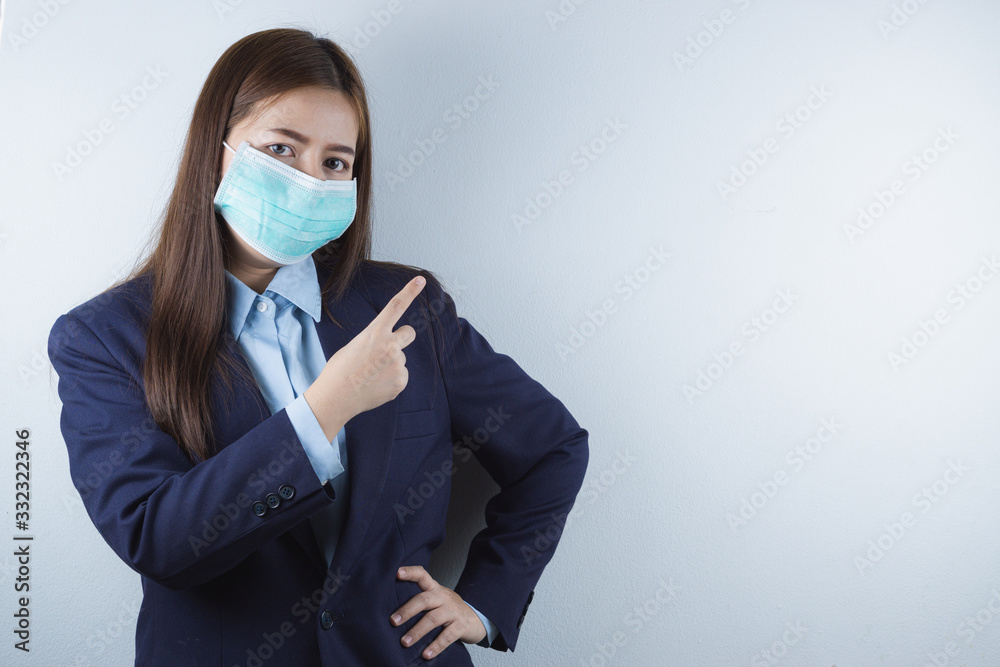 The business woman wearing protection face mask against coronavirus and 2.5 and cold. and her finger point to the white background. The business woman wearing protection face mask against coronavirus and 2.5 and cold. and her finger point to the white background.