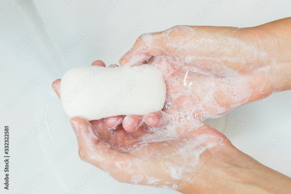 Fototapeta premium Man or woman washing hands, rubbing with soap in sink under water. Hand disinfection. Close up photo. Coronavirus, covid-19, 2019 pandemic prevention. disinfect, sanitize, epidemic concept .