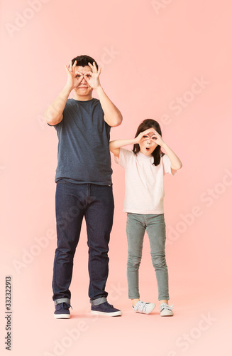 Funny Asian man and his little daughter on color background