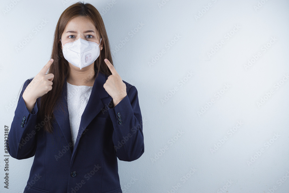 The business woman wearing protection face mask against coronavirus, PM 2.5 and cold, and her finger point on her mask. The business woman wearing protection face mask against coronavirus, PM 2.5 and cold, and her finger point on her mask.