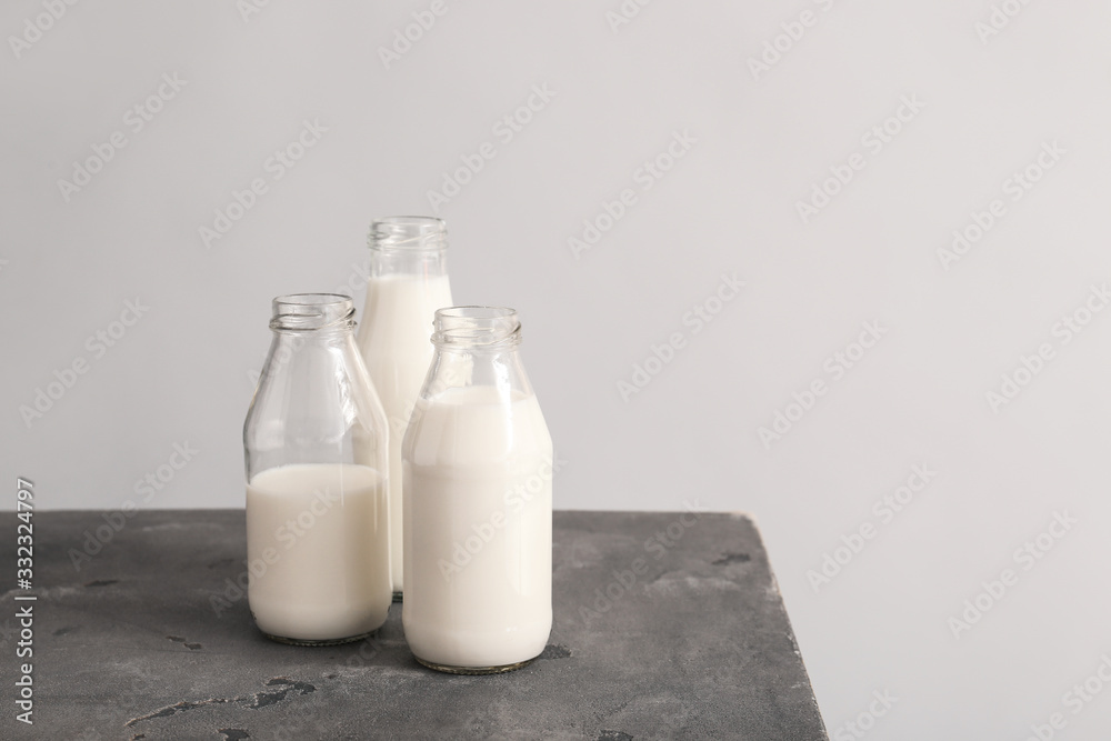 Glassware with fresh milk on table against grey background Glassware with fresh milk on table against grey background