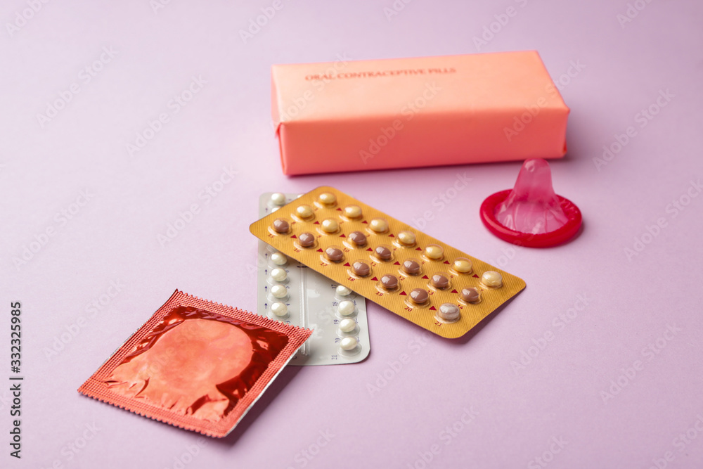 Contraceptive pills and condoms on color background Contraceptive pills and condoms on color background