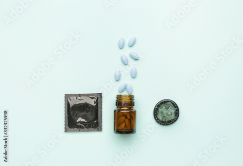 Bottle with sex pills and condoms on color background