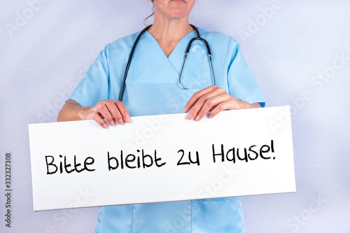 Pflegekraft mit Schild Bitte bleibt zu Hause photo