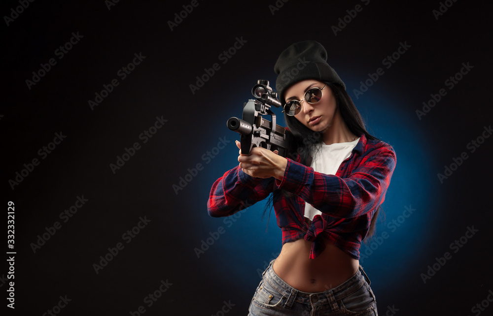 the girl in a checked shirt on a dark background with a shotgun