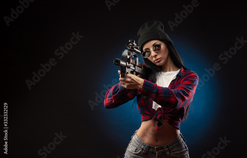 the girl in a checked shirt on a dark background with a shotgun