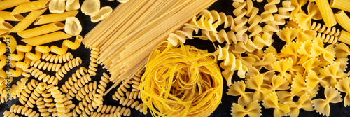 Italian pasta panoramic banner, a flat lay of many different pasta types, shot from the top on a black background