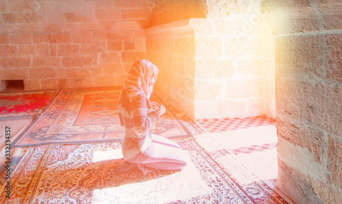 Young Muslim Woman Praying In Mosque with sun rays