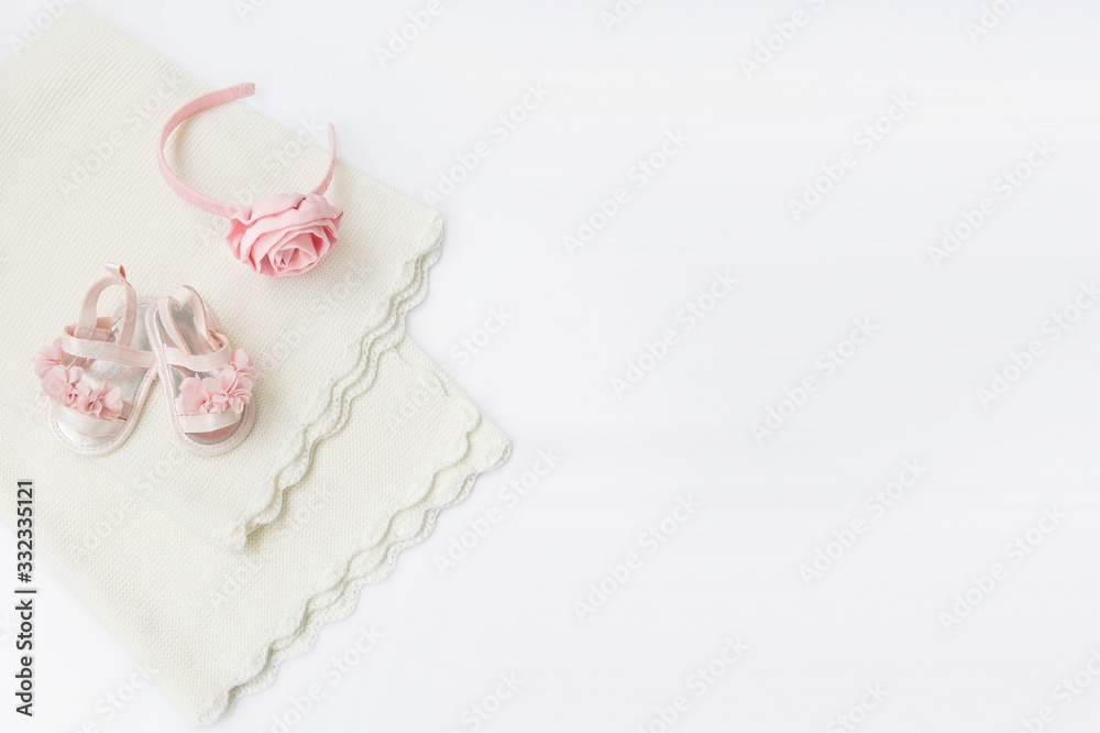 Folded rose knitted plaid. From above are a pair of white baby boots and dress. Folded rose knitted plaid. From above are a pair of white baby boots and dress.