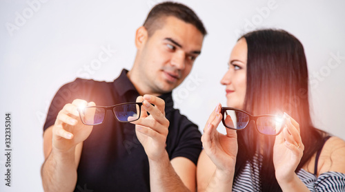 Beautiful woman and handsome man are holding eyeglasses in hands. White background. Close up